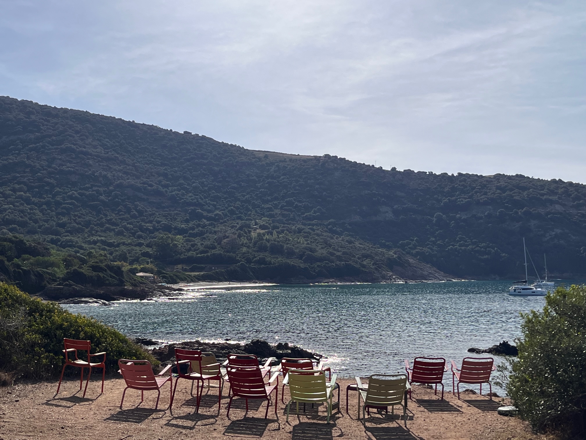 A sandy beach with chairs facing the bay